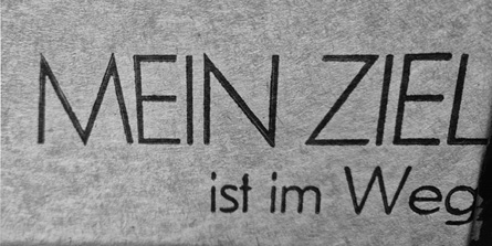 The text on a gray fabric reads "MEIN ZIEL ist im Weg" in bold black letters.
Description generated by AI